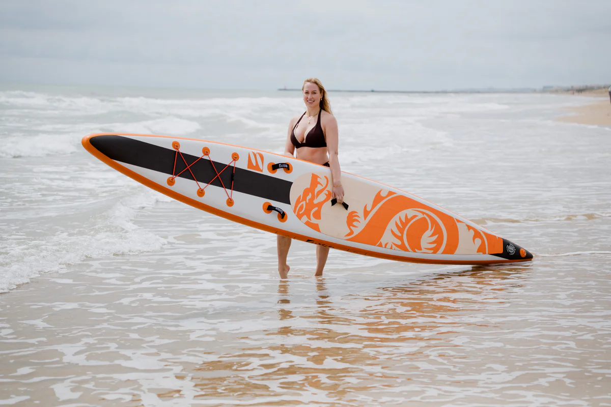 Bass SUP Dragon 14.5 – młoda kobieta z deską SUP na słonecznej plaży w Hiszpanii
