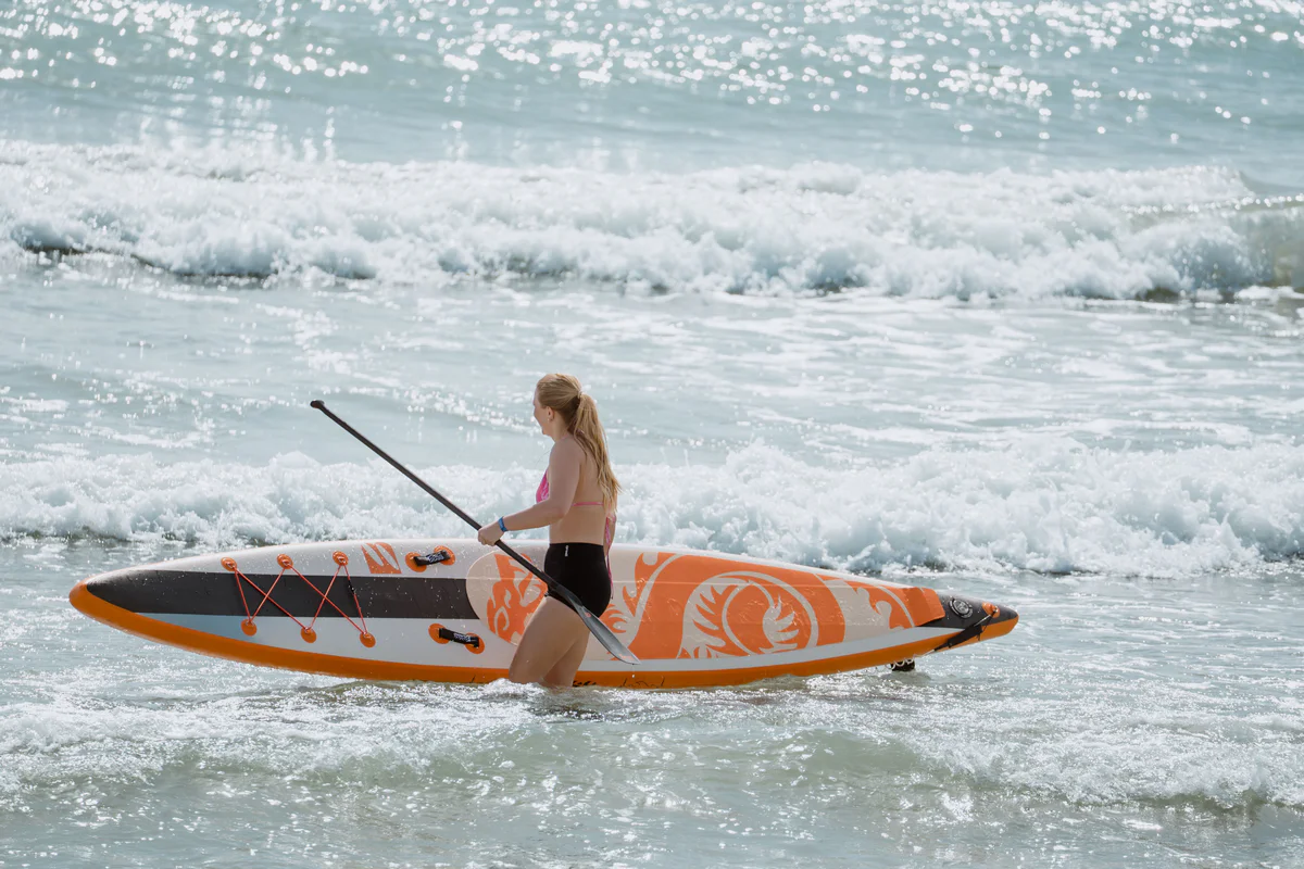 Bass SUP Dragon 14.5 – kobieta pozuje z deską SUP nad morzem w Hiszpanii