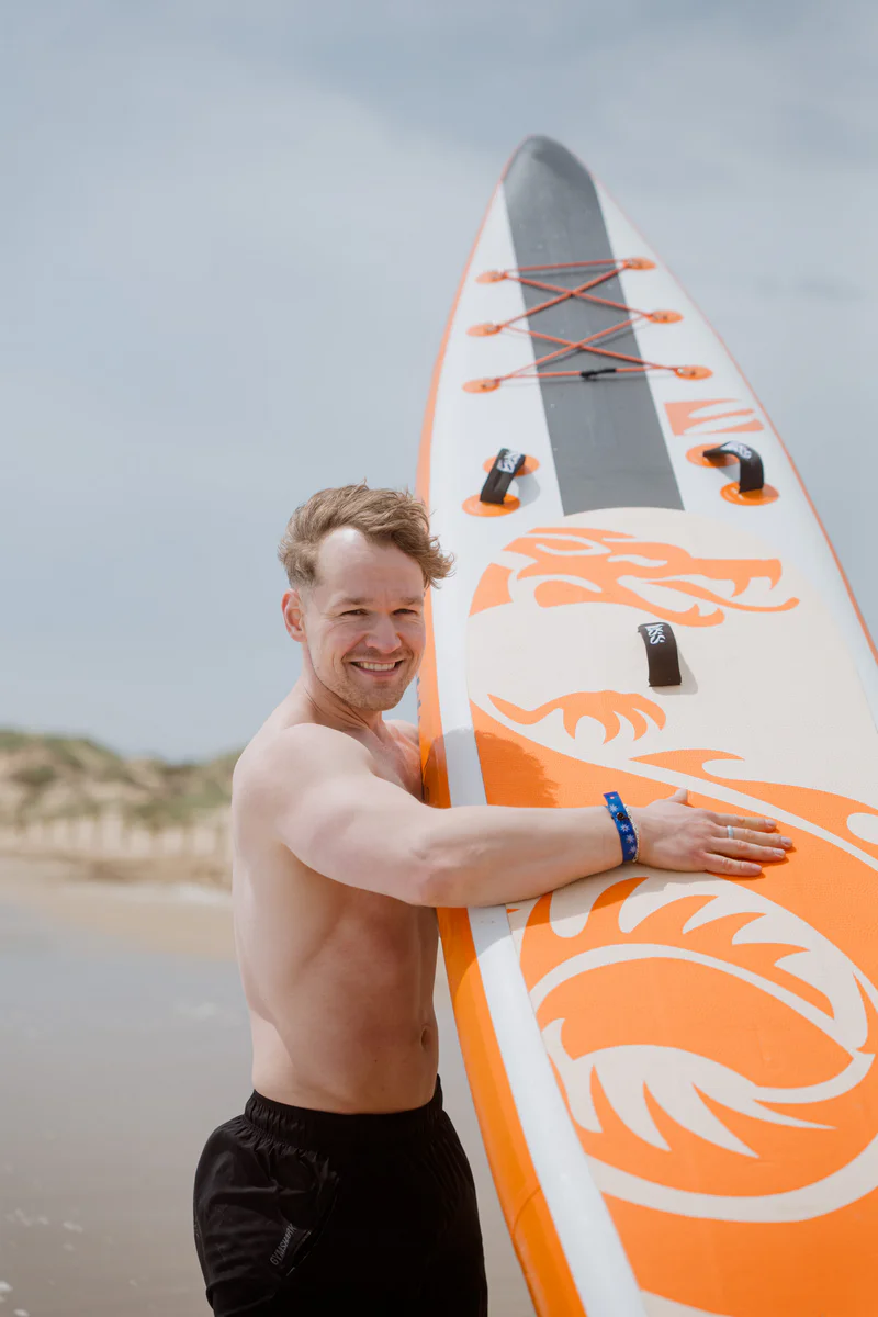 Bass SUP Dragon 14.6 – mężczyzna trzymający deskę SUP na tle morza w Hiszpanii