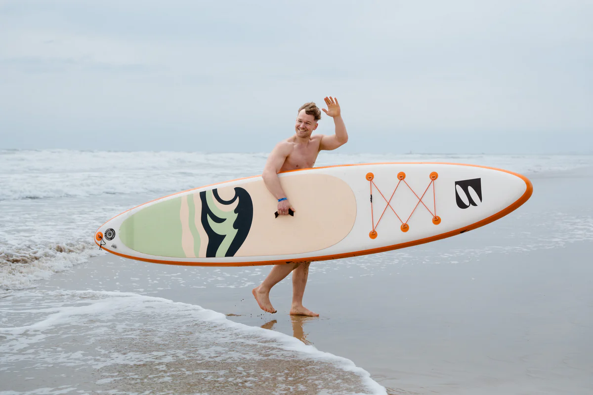 Bass SUP Twin 12 – young man with SUP board on a sunny beach in Spain