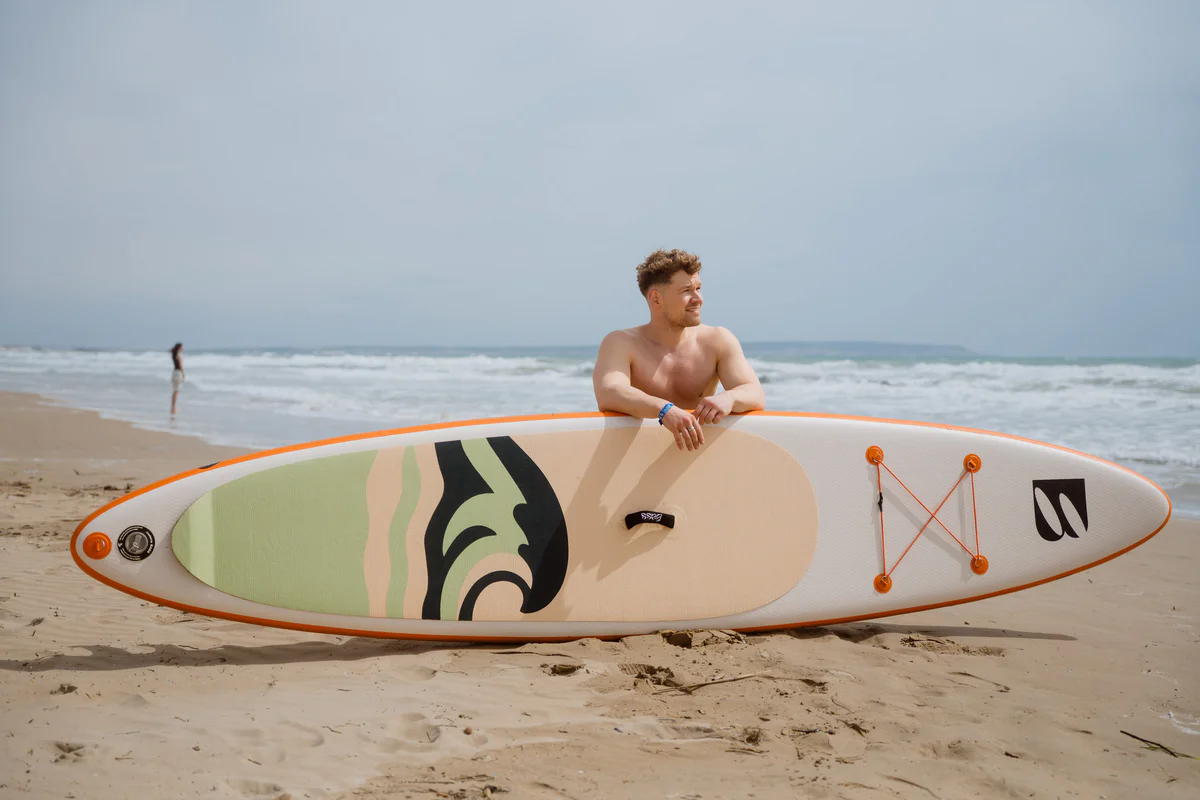 Bass SUP TwinSR – młody mężczyzna z deską SUP na słonecznej plaży w Hiszpanii