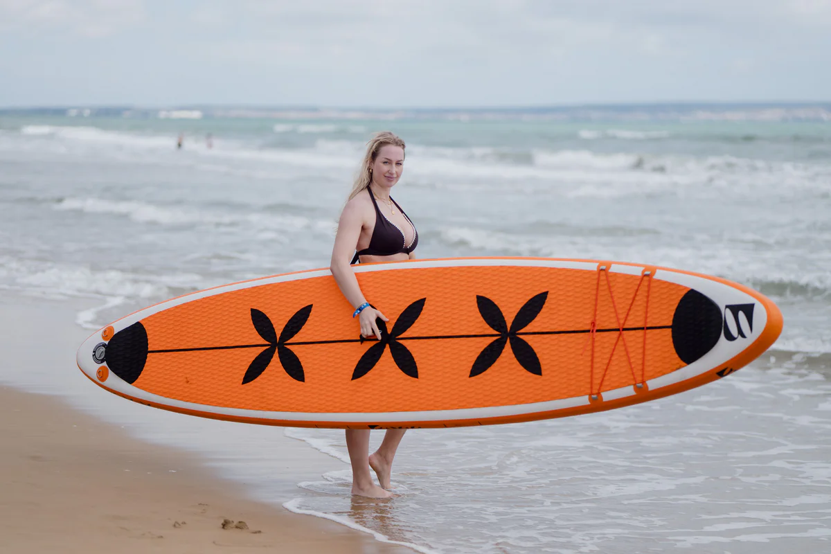 Bass SUP Freestyle – młoda kobieta z deską SUP na słonecznej plaży w Hiszpanii
