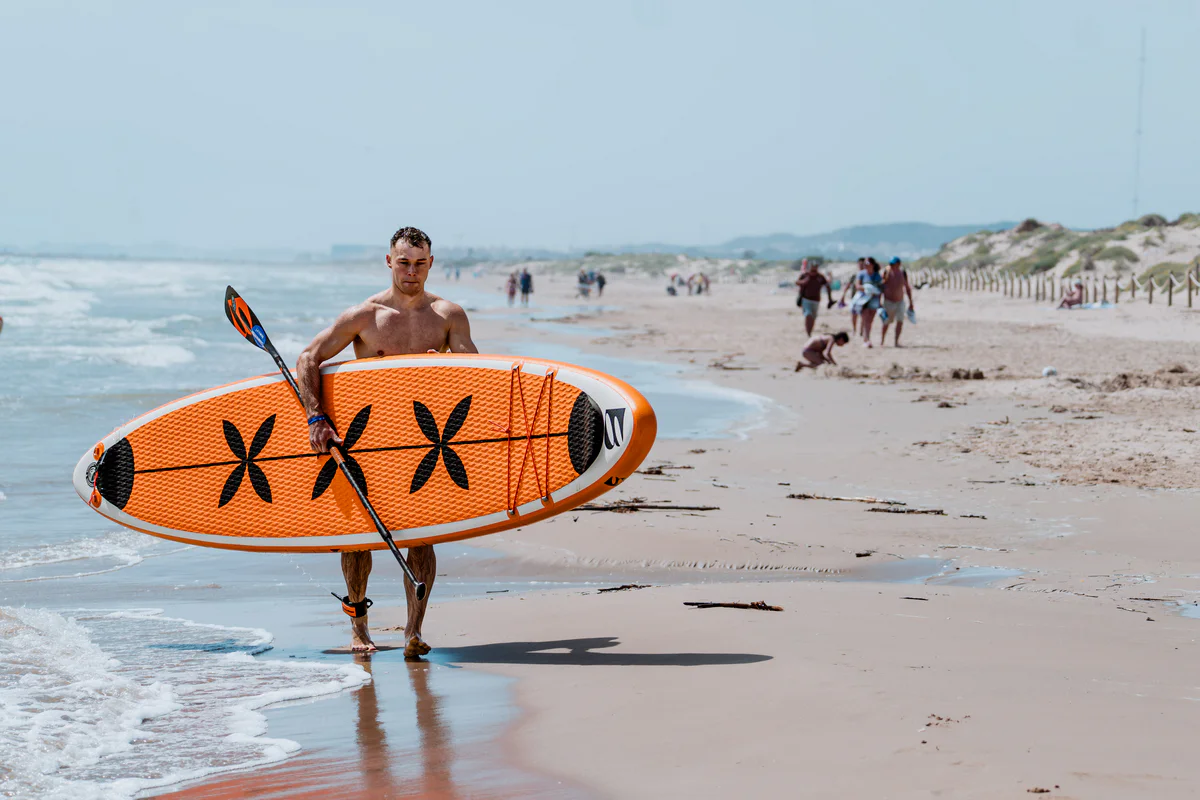 Bass SUP Freestyle – młody mężczyzna z deską SUP nad morzem w Hiszpanii