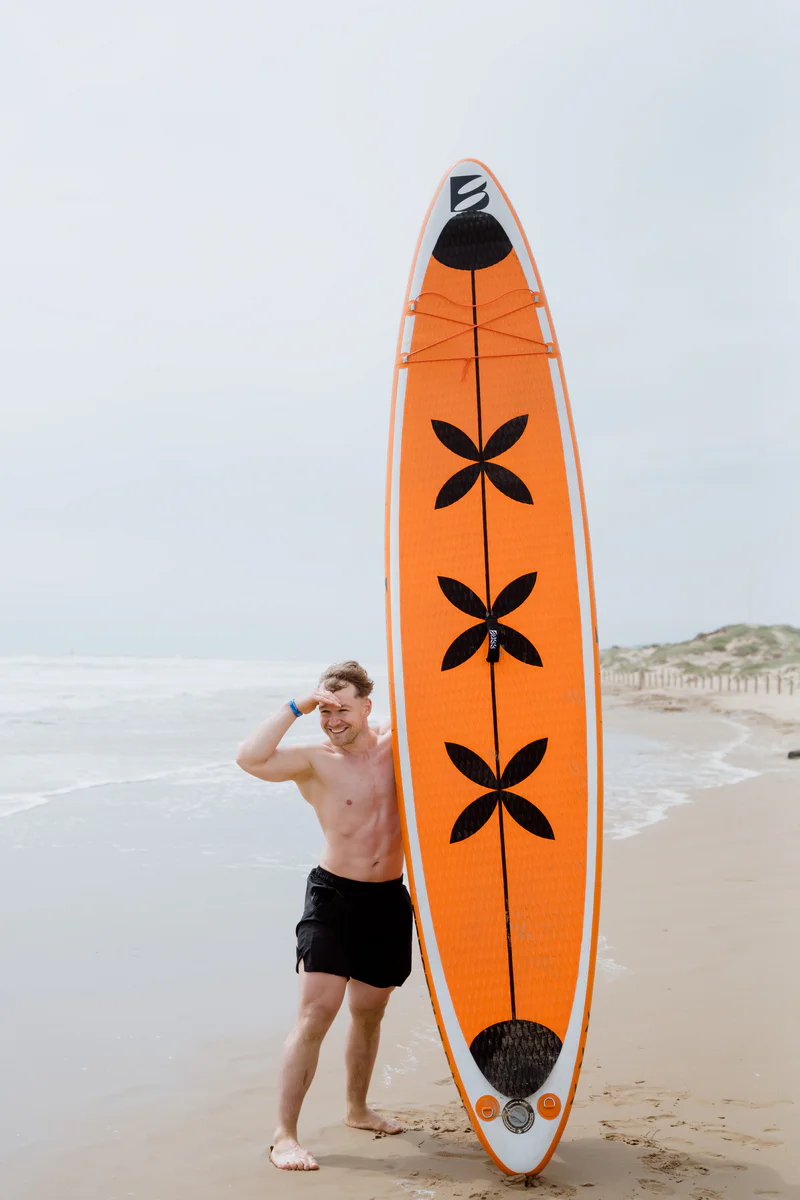Bass SUP Freestyle – mężczyzna trzymający deskę SUP na plaży w Hiszpanii