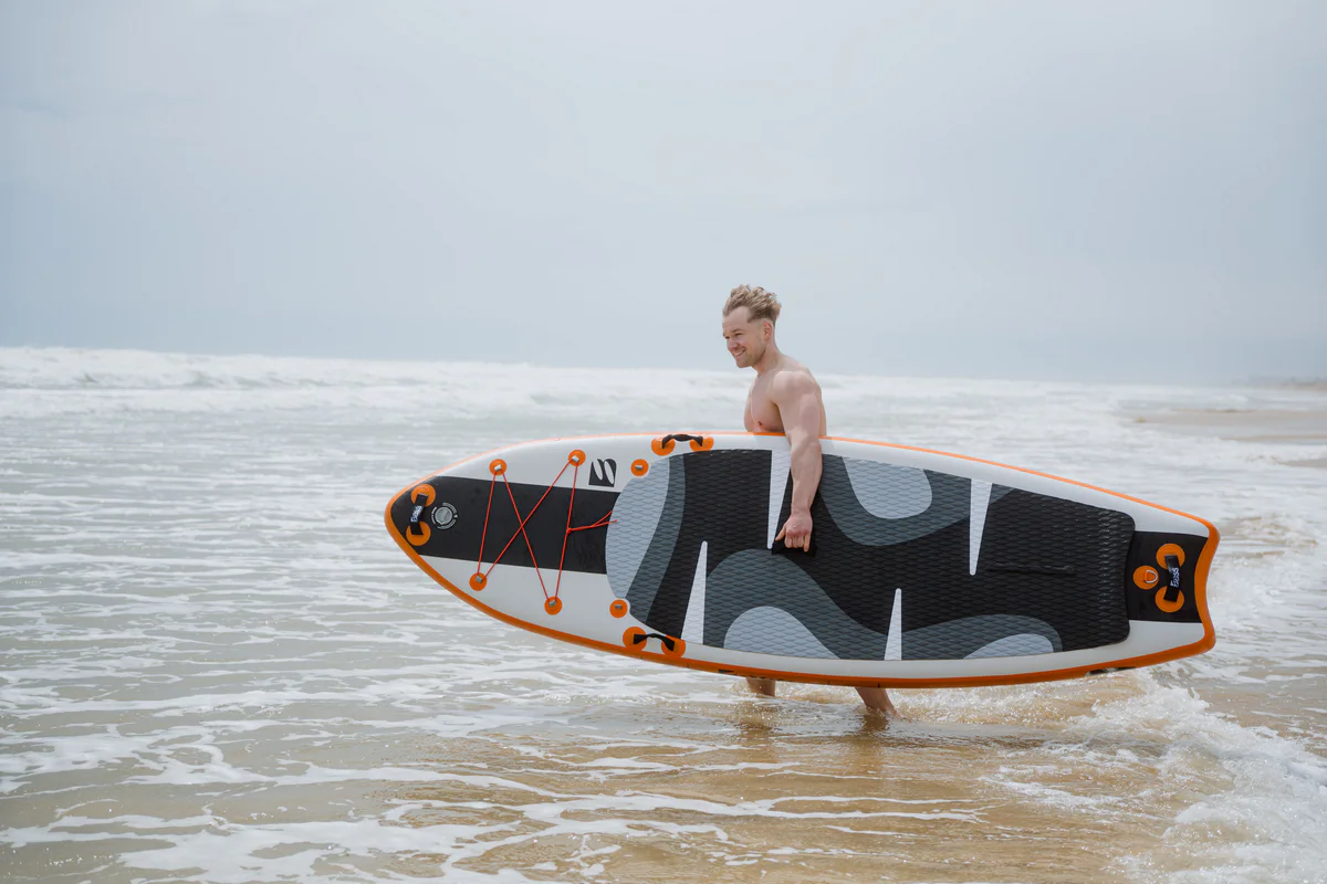 Bass SUP White Water 9.9 – młody mężczyzna z deską SUP na plaży w Hiszpanii