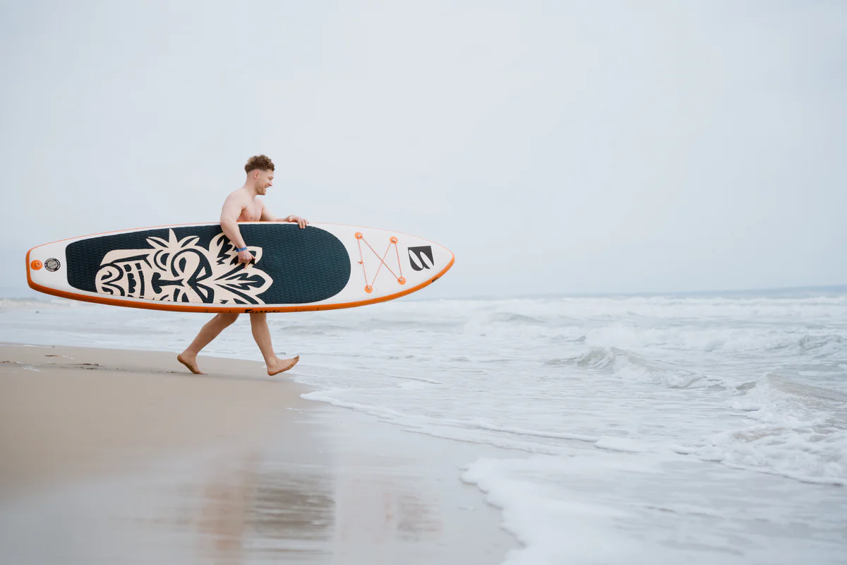 Bass SUP Wind and Wing 10 – mężczyzna trzymający deskę SUP na plaży w Hiszpanii