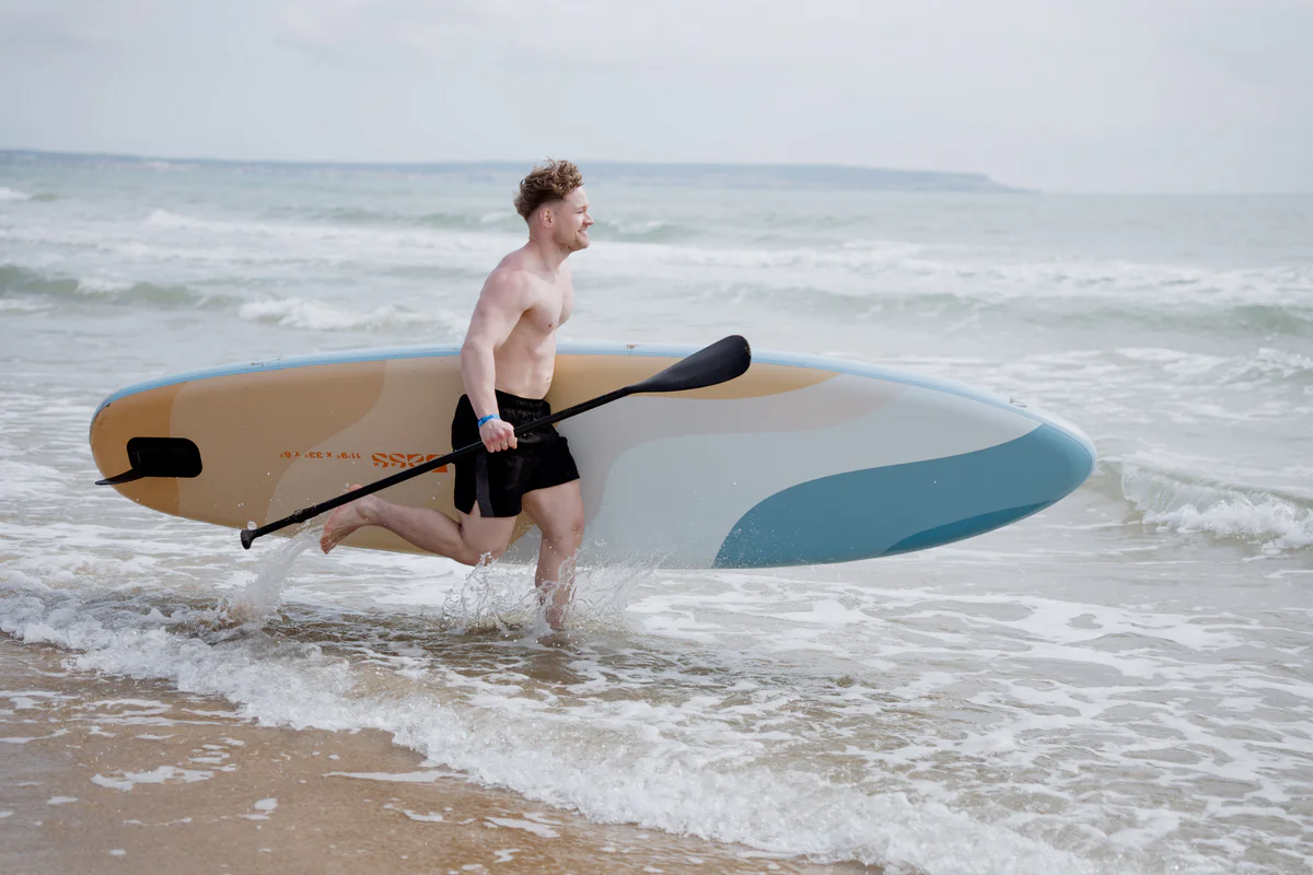 Blight SUP 11.9 – młody mężczyzna z deską SUP na słonecznej plaży w Hiszpanii
